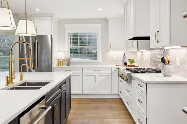 kitchen with stainless steel appliances, a sink, white cabinets, decorative backsplash, and pendant lighting