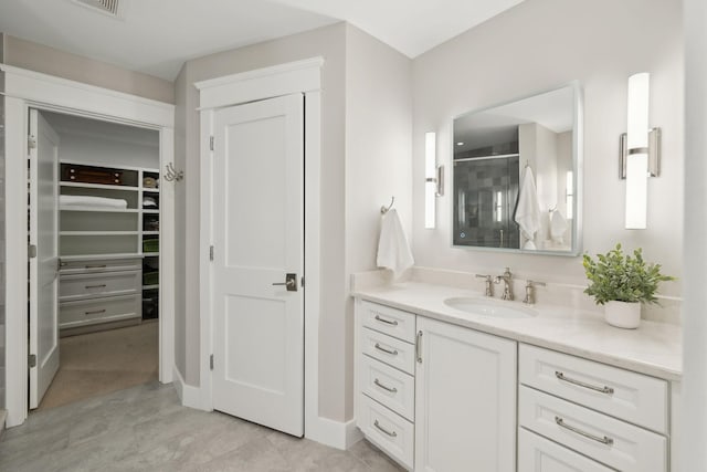 bathroom with a shower stall, vanity, and a spacious closet