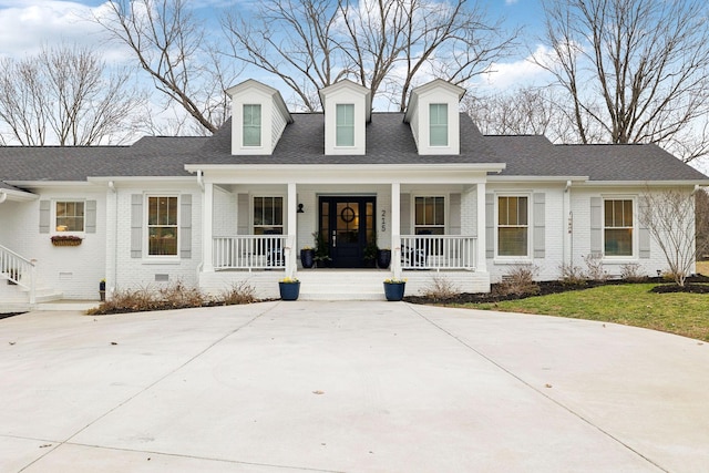 cape cod home with crawl space, covered porch, a shingled roof, and brick siding