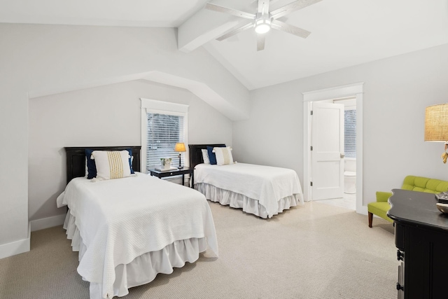 bedroom featuring lofted ceiling with beams, light colored carpet, a ceiling fan, baseboards, and ensuite bath