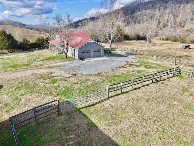 view of yard featuring a detached garage, fence, and a rural view