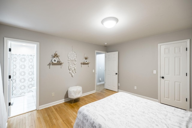 bedroom with light wood-style flooring, baseboards, and ensuite bathroom