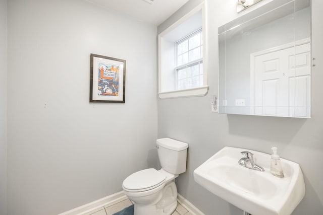 half bath featuring baseboards, a sink, toilet, and tile patterned floors