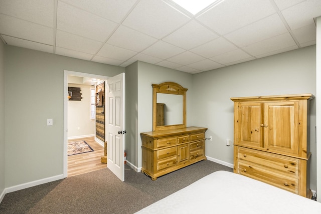 bedroom with dark carpet, a paneled ceiling, and baseboards