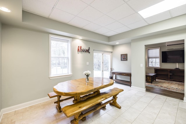 dining area with a paneled ceiling, baseboards, and a wealth of natural light