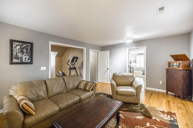 living room with wood finished floors, visible vents, and baseboards