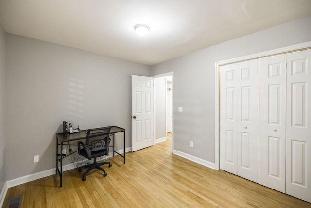 home office with light wood-style flooring, visible vents, and baseboards