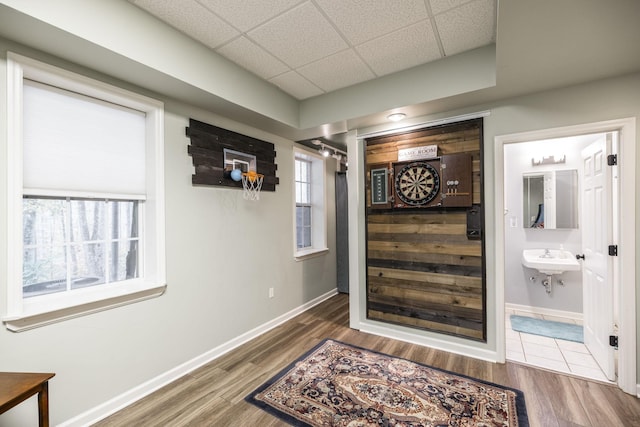 corridor with a drop ceiling, a sink, baseboards, and wood finished floors