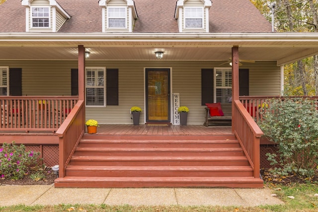 doorway to property featuring covered porch and a shingled roof