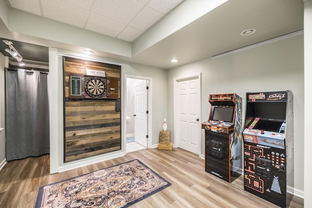 interior space with a paneled ceiling, baseboards, and wood finished floors