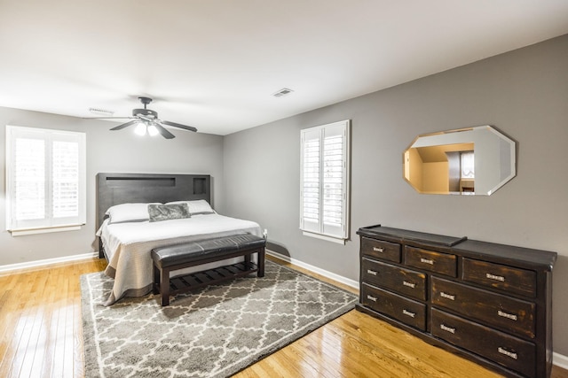 bedroom featuring baseboards, a ceiling fan, visible vents, and light wood-style floors