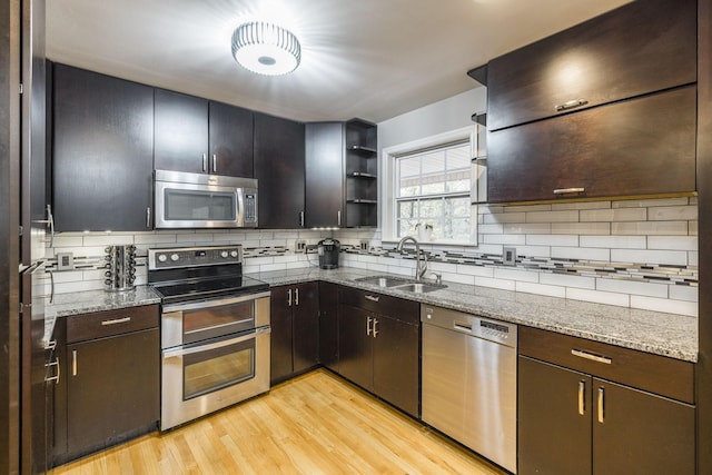 kitchen with stainless steel appliances, a sink, light wood-style flooring, and tasteful backsplash