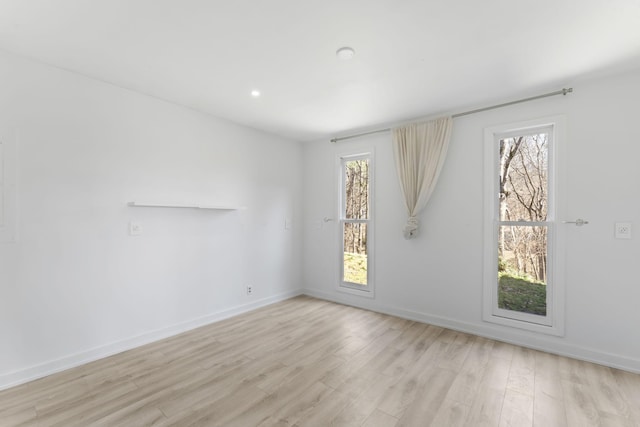 spare room featuring baseboards and light wood finished floors