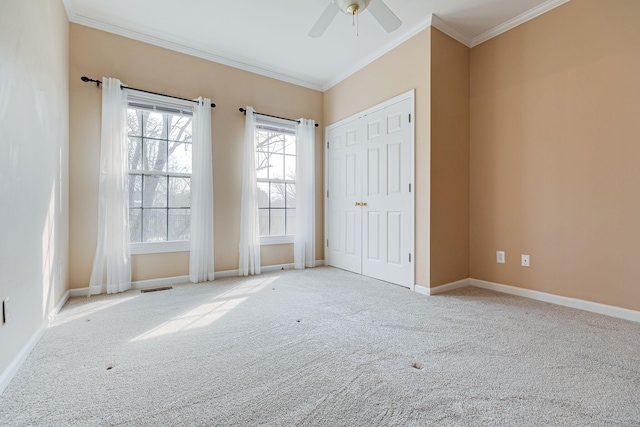 spare room with baseboards, visible vents, a ceiling fan, crown molding, and carpet flooring