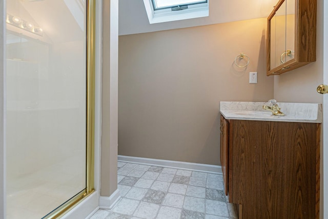 bathroom with a skylight, a shower stall, vanity, and baseboards