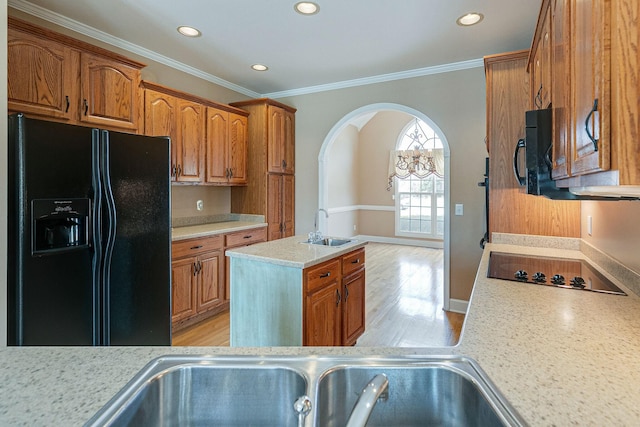 kitchen with black appliances, light wood finished floors, a sink, and light countertops