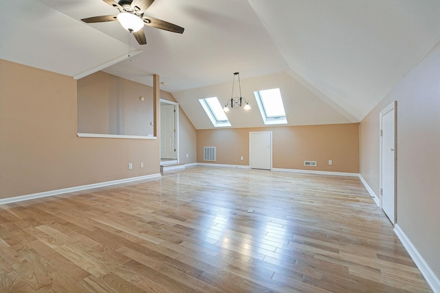 additional living space with light wood finished floors, vaulted ceiling with skylight, visible vents, and baseboards