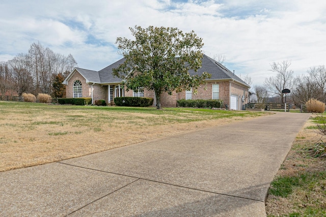 view of front of house with an attached garage, driveway, a front lawn, and brick siding