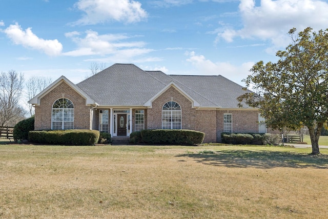 view of front of property with brick siding, a front yard, and a shingled roof