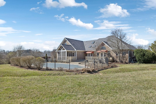 rear view of property with a fenced in pool, a lawn, and fence