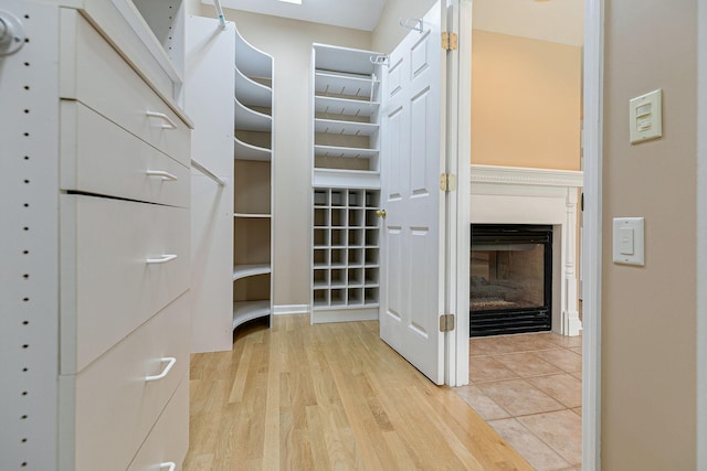 spacious closet with a glass covered fireplace and wood finished floors