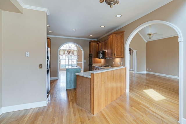 kitchen featuring arched walkways, freestanding refrigerator, a center island, light wood-style floors, and black microwave