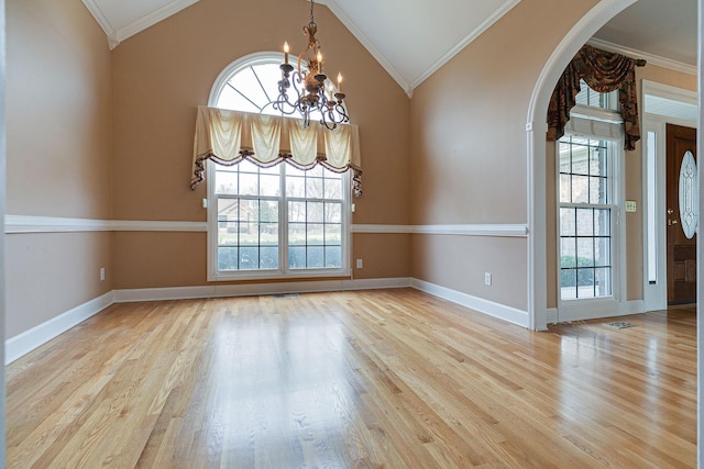 spare room with a chandelier, ornamental molding, baseboards, and wood finished floors