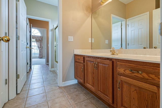 full bathroom with a shower with shower door, vanity, baseboards, and tile patterned floors