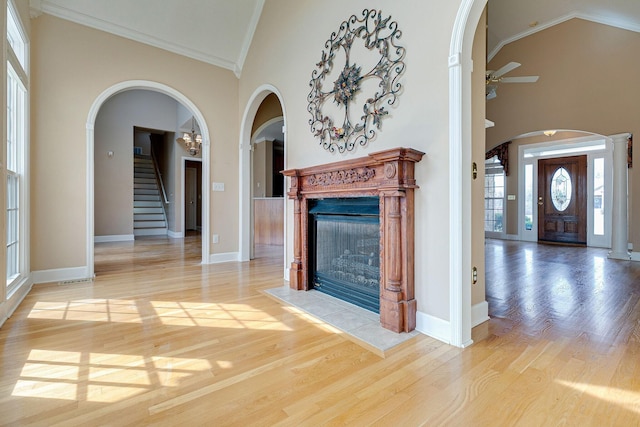 unfurnished living room with high vaulted ceiling, a tiled fireplace, and wood finished floors