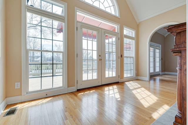 doorway to outside featuring visible vents, arched walkways, wood finished floors, and french doors