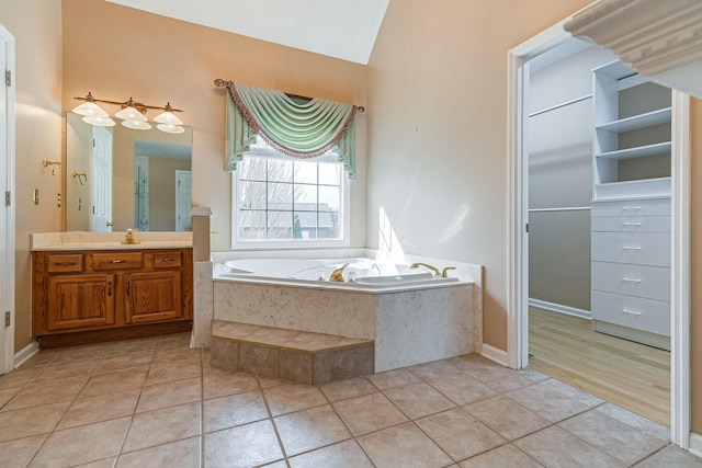 full bath with a garden tub, tile patterned flooring, vanity, and lofted ceiling