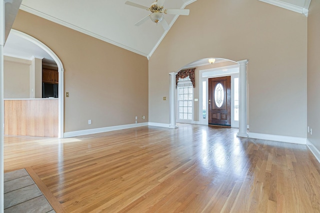 entrance foyer featuring baseboards, arched walkways, ornamental molding, light wood-type flooring, and ornate columns