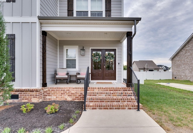 doorway to property featuring a yard, a porch, board and batten siding, and crawl space