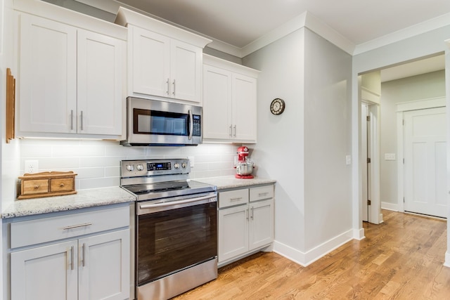 kitchen with stainless steel appliances, ornamental molding, backsplash, and light wood-style floors