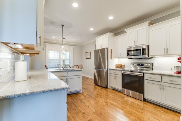 kitchen featuring appliances with stainless steel finishes, a sink, light wood finished floors, and tasteful backsplash