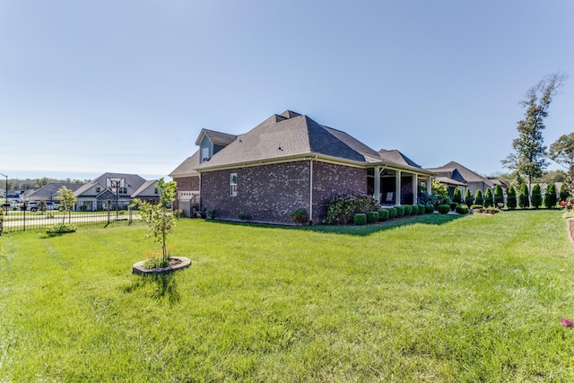 view of home's exterior featuring brick siding, a lawn, and fence