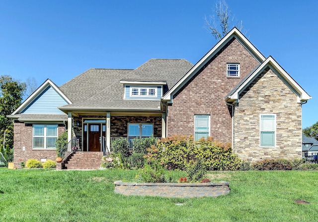 craftsman house with stone siding, roof with shingles, a front lawn, and brick siding