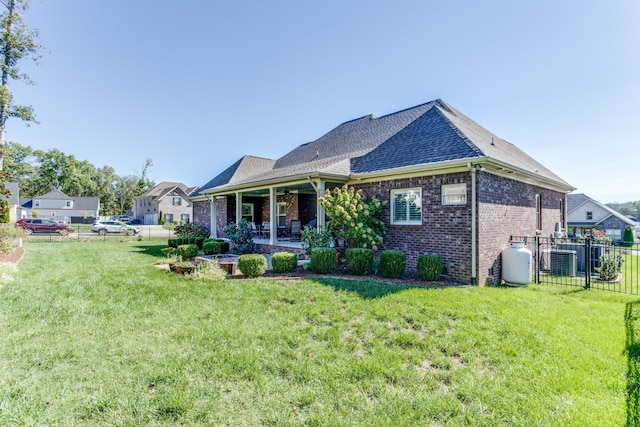 rear view of house with brick siding, a patio, a lawn, fence, and cooling unit