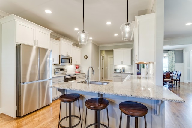 kitchen featuring a peninsula, ornamental molding, stainless steel appliances, and a sink