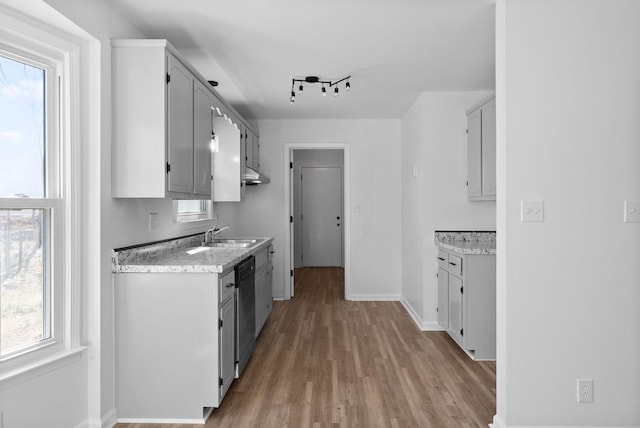 kitchen with baseboards, dishwashing machine, light wood-style flooring, a sink, and track lighting