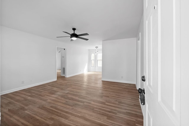 spare room with ceiling fan, visible vents, baseboards, and dark wood-type flooring