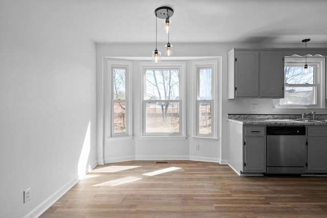 kitchen with decorative light fixtures, baseboards, stainless steel dishwasher, and wood finished floors