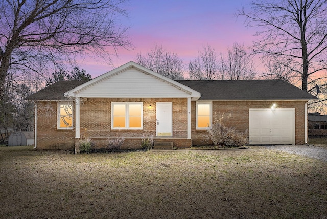 view of front facade with an attached garage, a yard, and brick siding