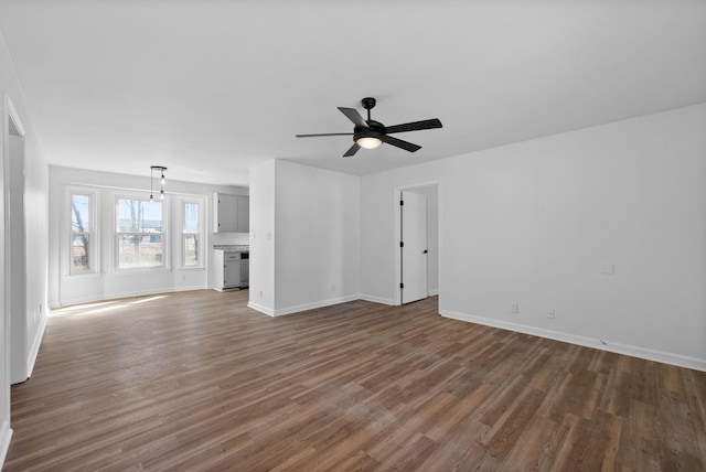 unfurnished living room with ceiling fan, baseboards, and wood finished floors