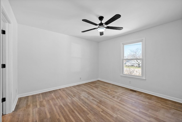 spare room with ceiling fan, wood finished floors, visible vents, and baseboards