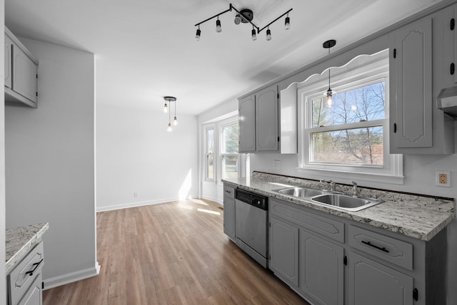 kitchen featuring dishwasher, light countertops, wood finished floors, and a sink