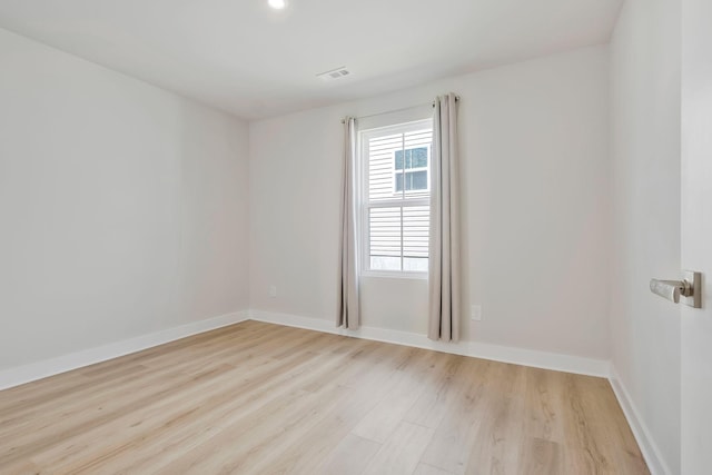 unfurnished room featuring light wood-type flooring, visible vents, and baseboards