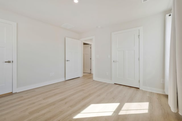 unfurnished bedroom featuring light wood-style floors, visible vents, and baseboards