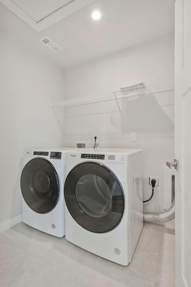 clothes washing area featuring laundry area, visible vents, washer and clothes dryer, and light tile patterned floors