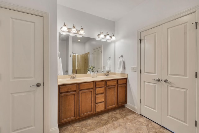 full bath with double vanity, a stall shower, a sink, and baseboards